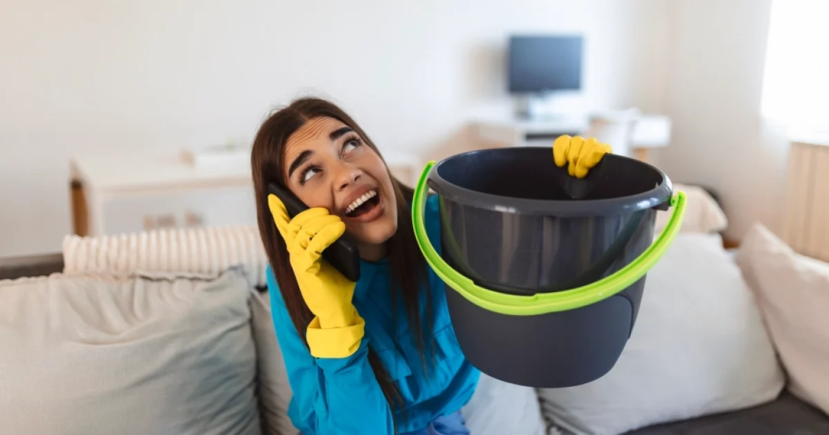 shocked-woman-calling-plumber-while-collecting-water-leaking-from-ceiling-using-utensil